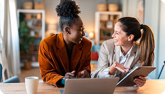 Duas profissionais conversando em uma reunião de trabalho